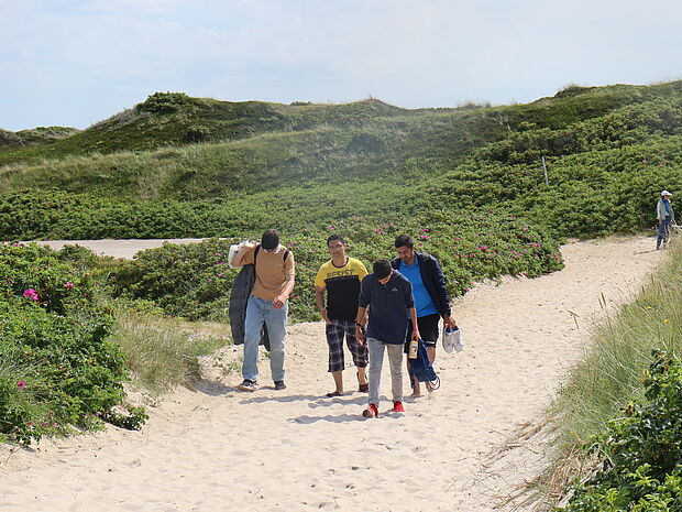Junge Männer wandern durch Dünen